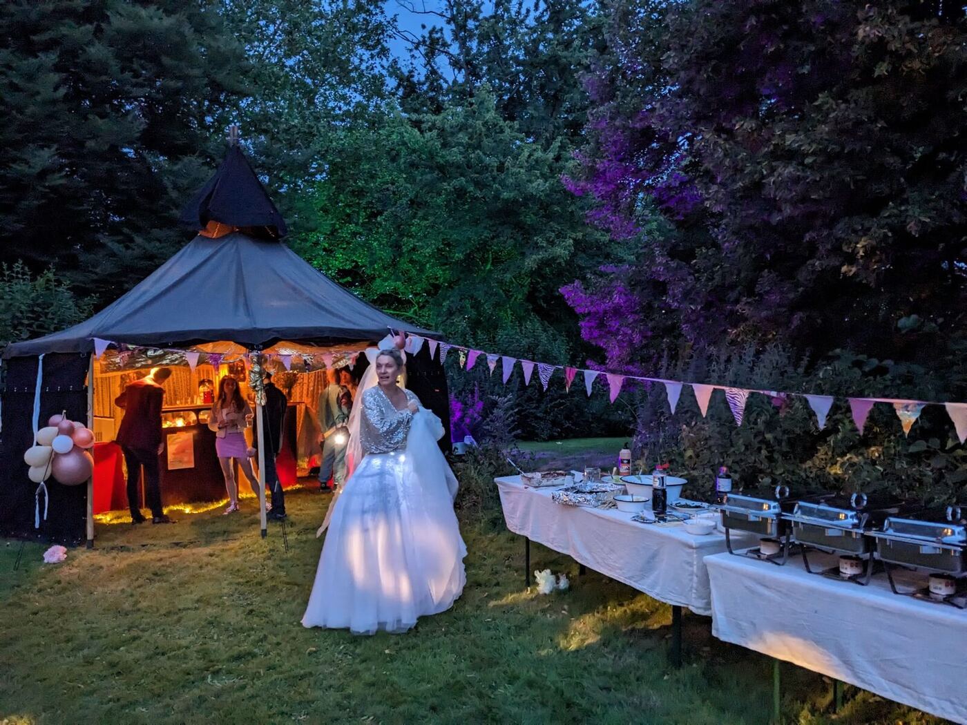 Schwarze Jurte als Hochzeitszelt im Garten mit Lichterketten und Buffet